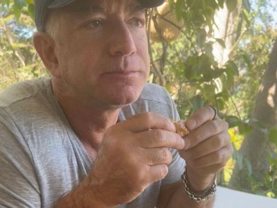 Jeff Bezos is eating a burger in the picture.